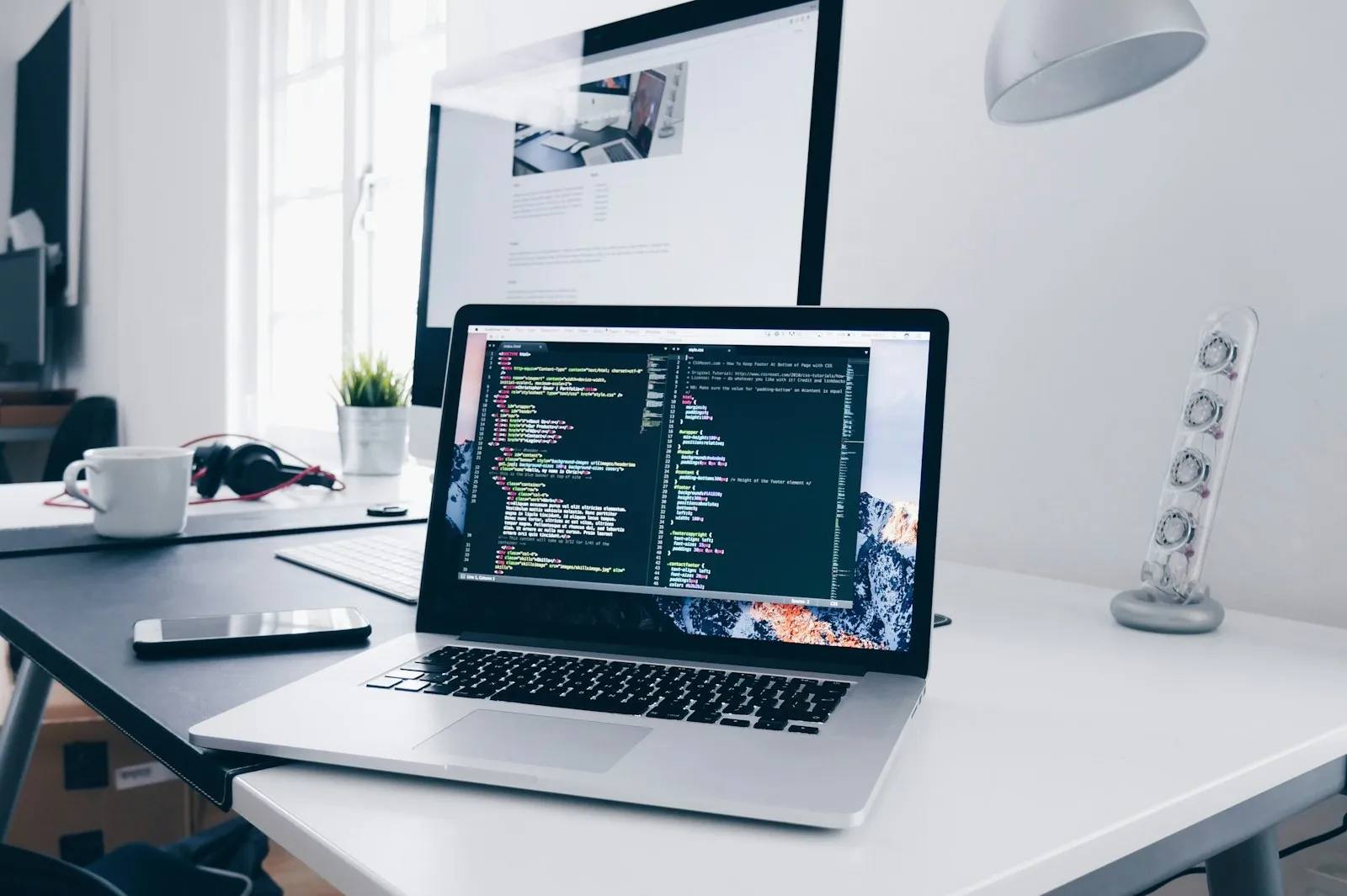 A laptop showing website code on a bright desk